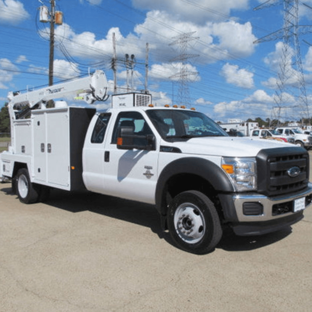 A white mechanic service truck with a utility body and rear‑mounted crane is parked on a paved lot under a partly cloudy sky.